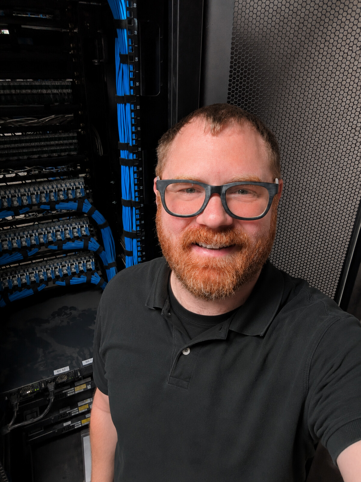 Tyler in front of a freshly cabled network rack